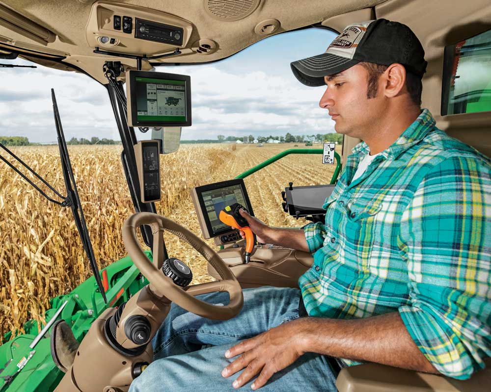 A farmer operates the John Deere S700 combine, available at C & B Operations.