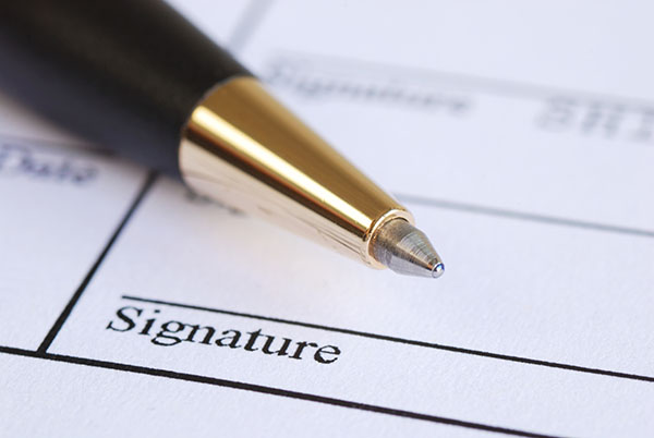 Sign the name on a paper with a pen